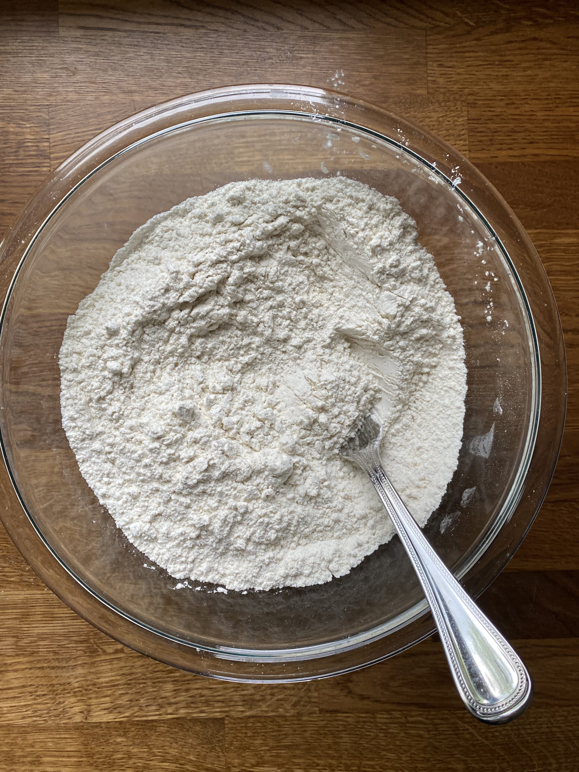 Combining dry ingredients in large glass bowl for sourdough discard flatbread dough.
