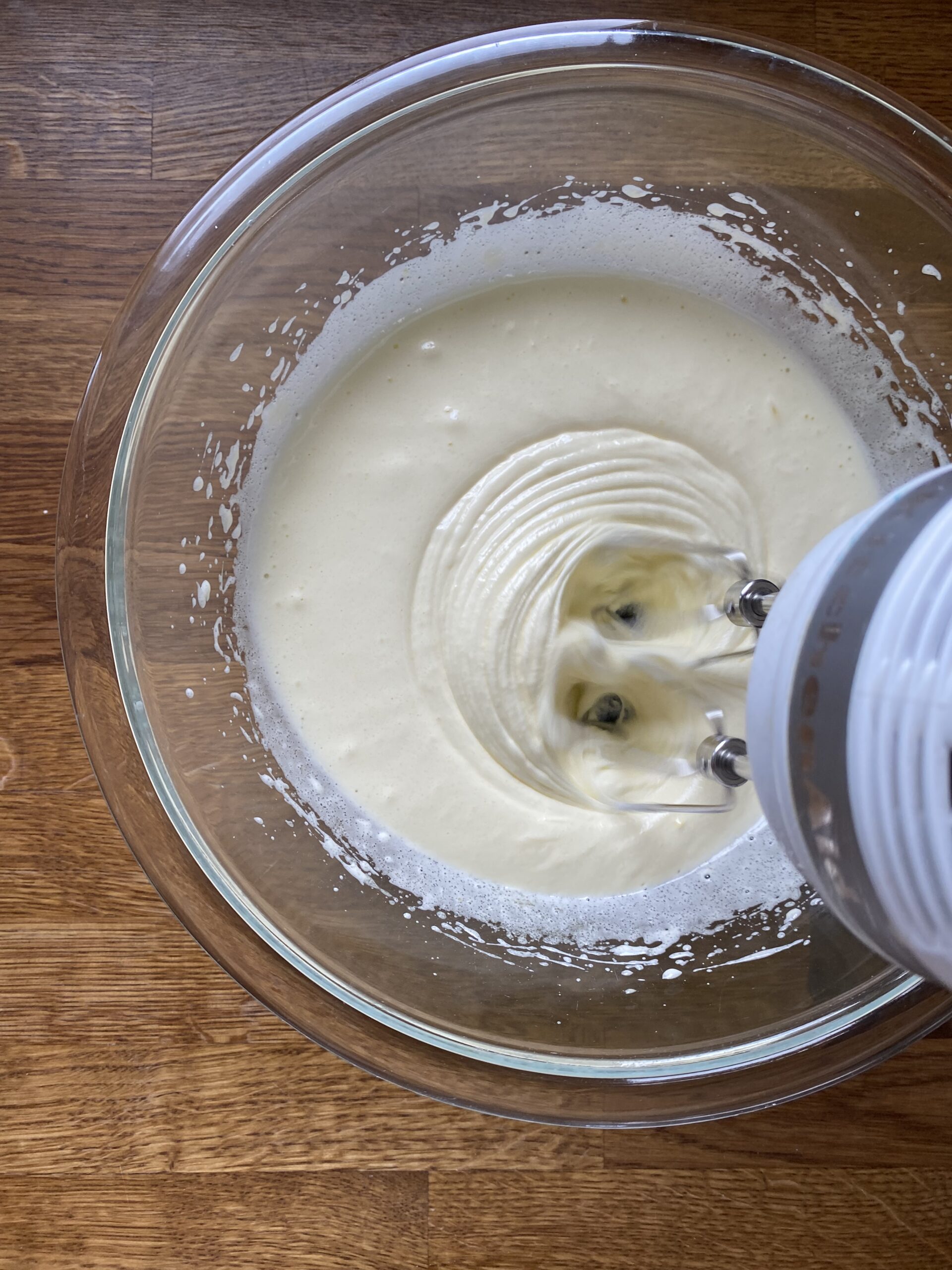 Beating eggs and sugar to ribbon stage in a glass bowl.