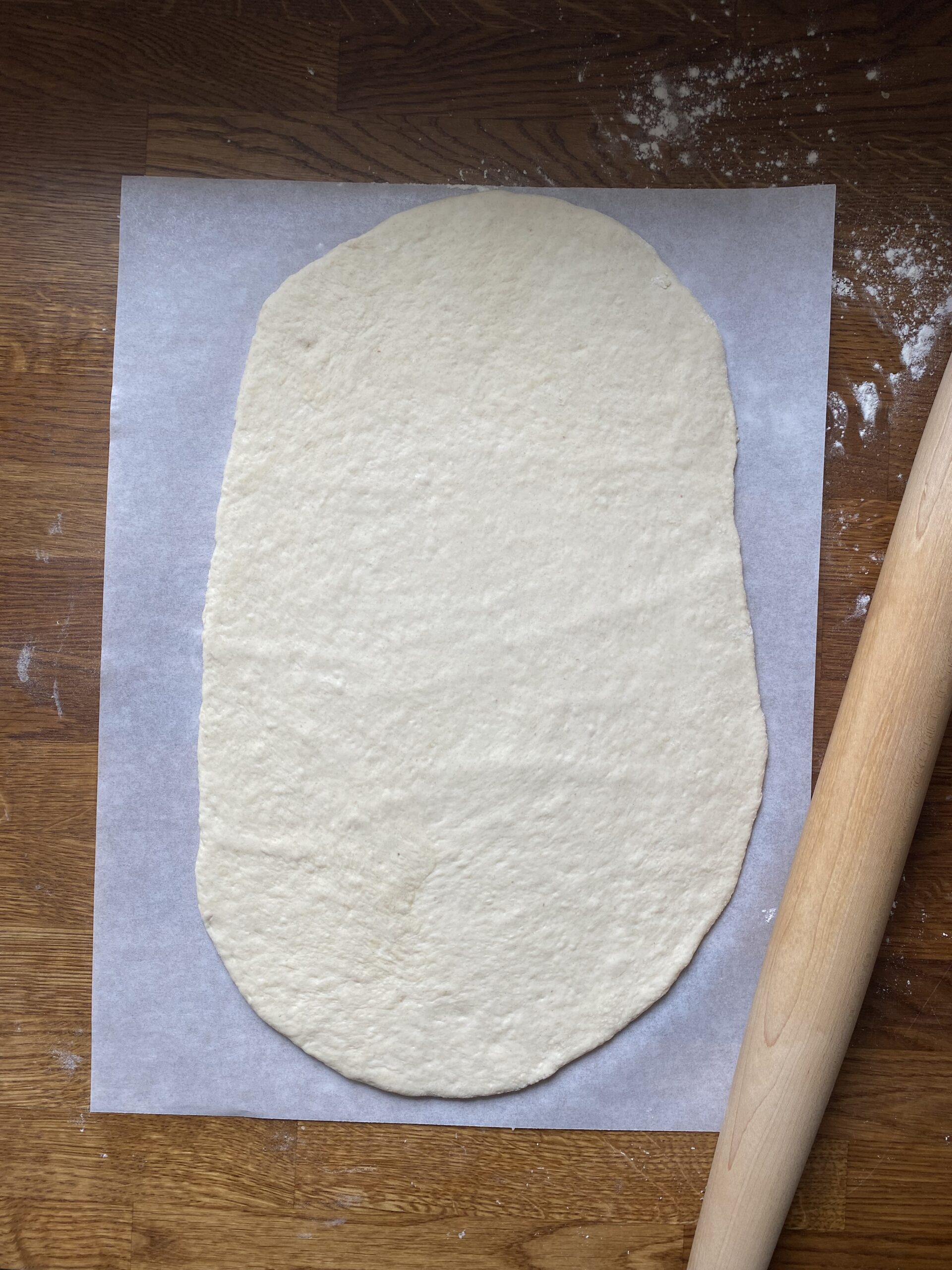 Flatbread rolled out and on a piece of parchment paper for easy transfer to the grill.