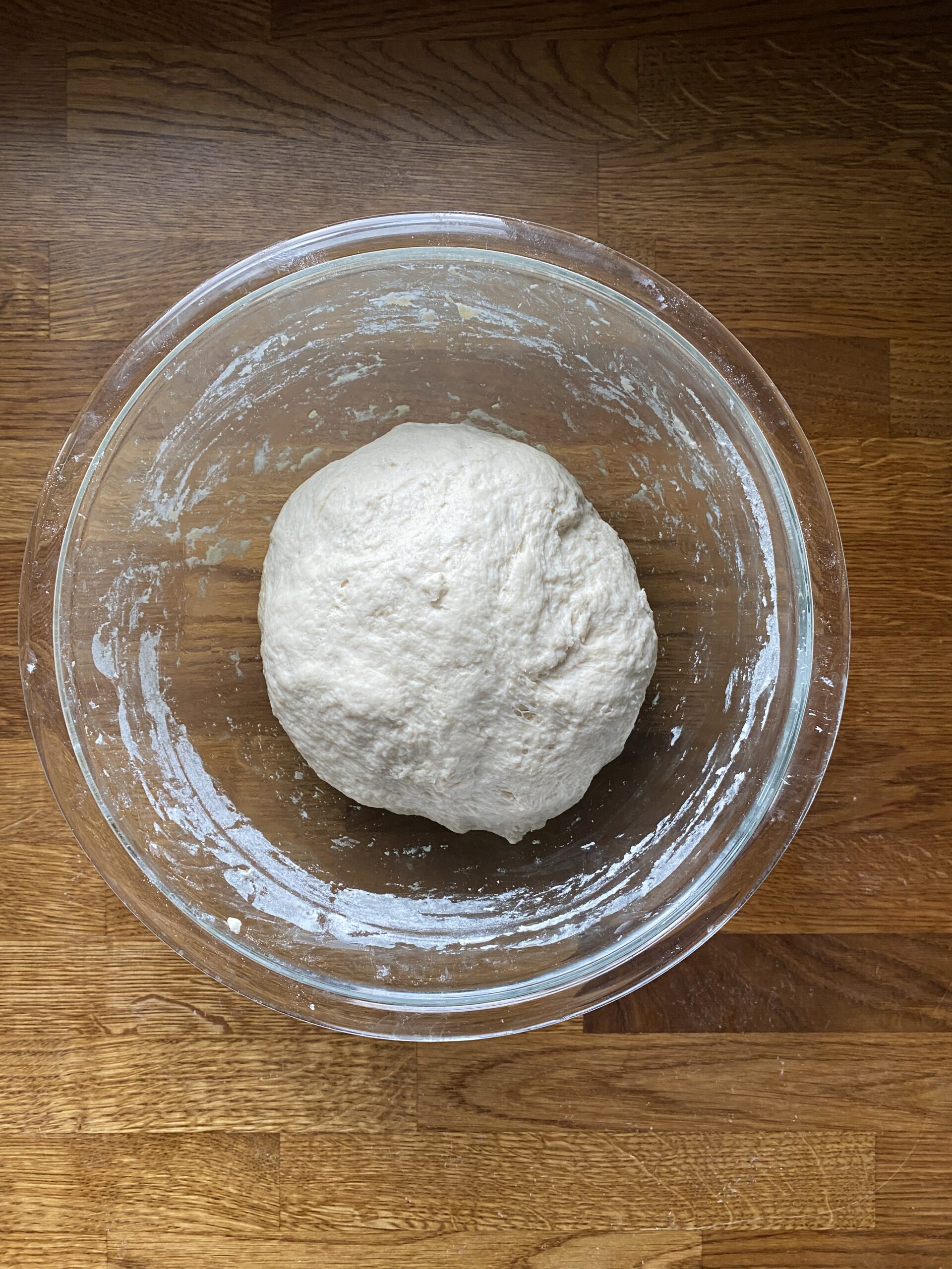 Sourdough flatbread dough resting in an oiled glass bowl.