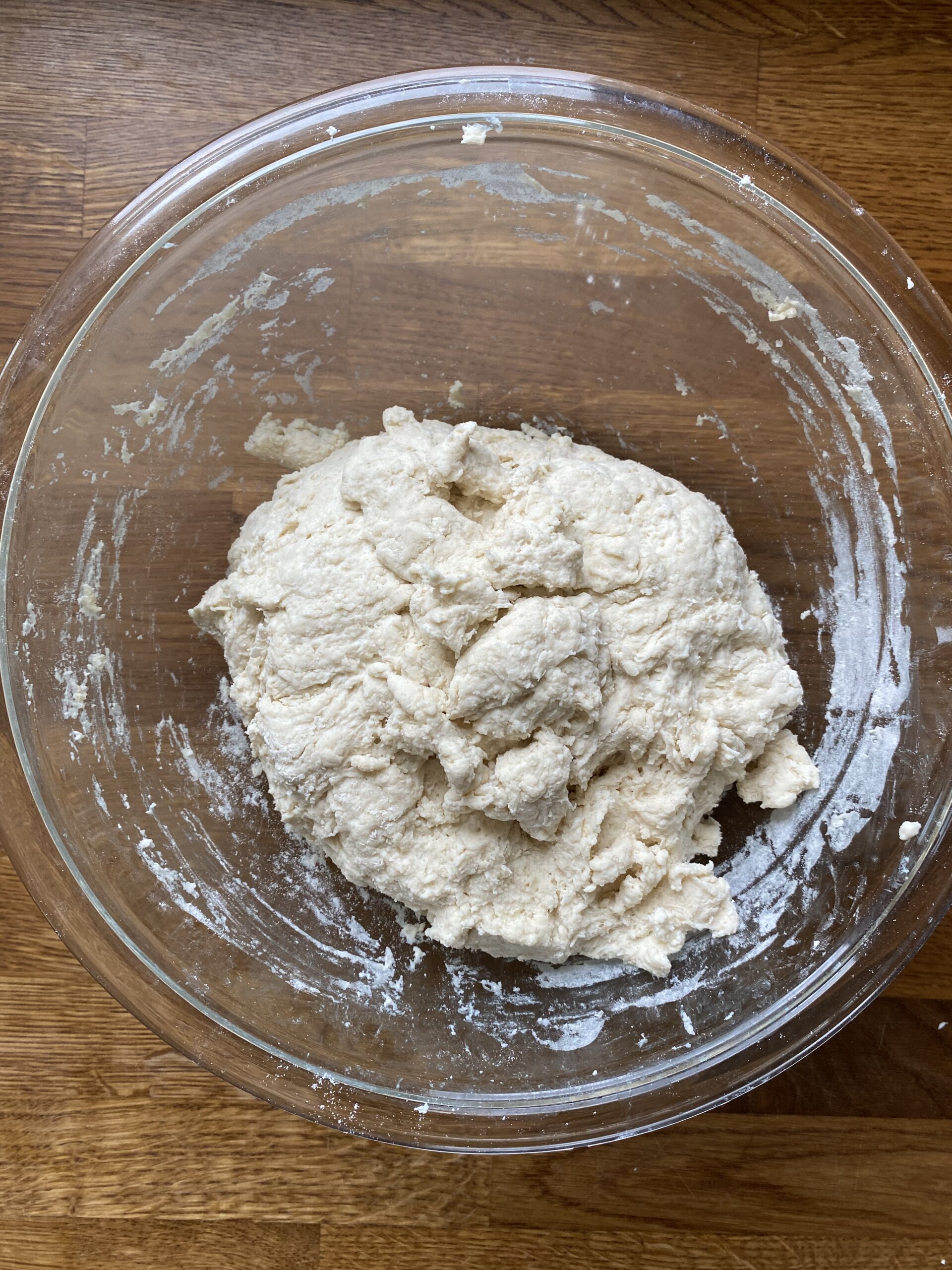 Shaggy sourdough discard flatbread dough in a glass bowl after hand mixing.