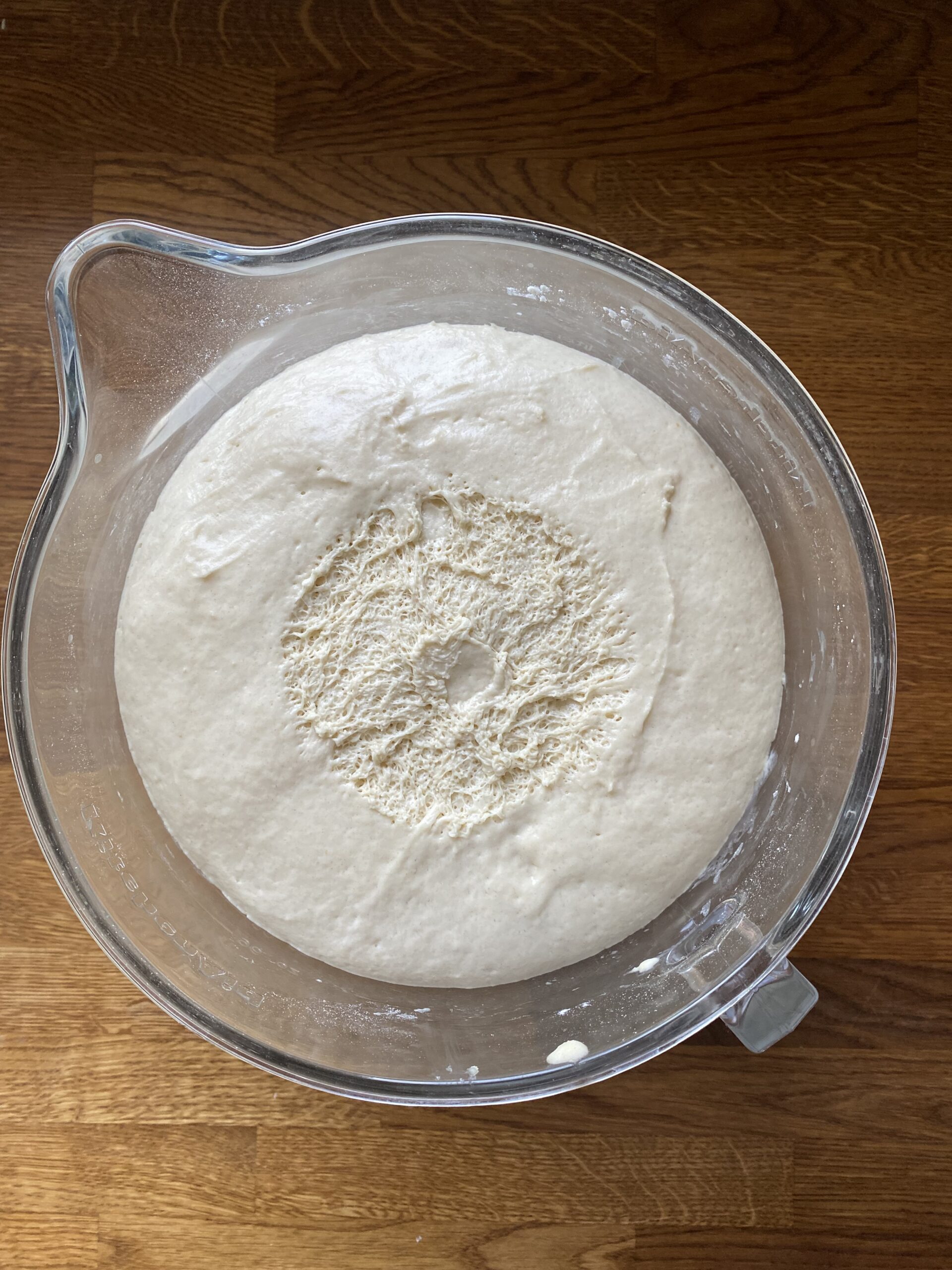 Sourdough discard hoagie roll dough after the first rise in a glass bowl.