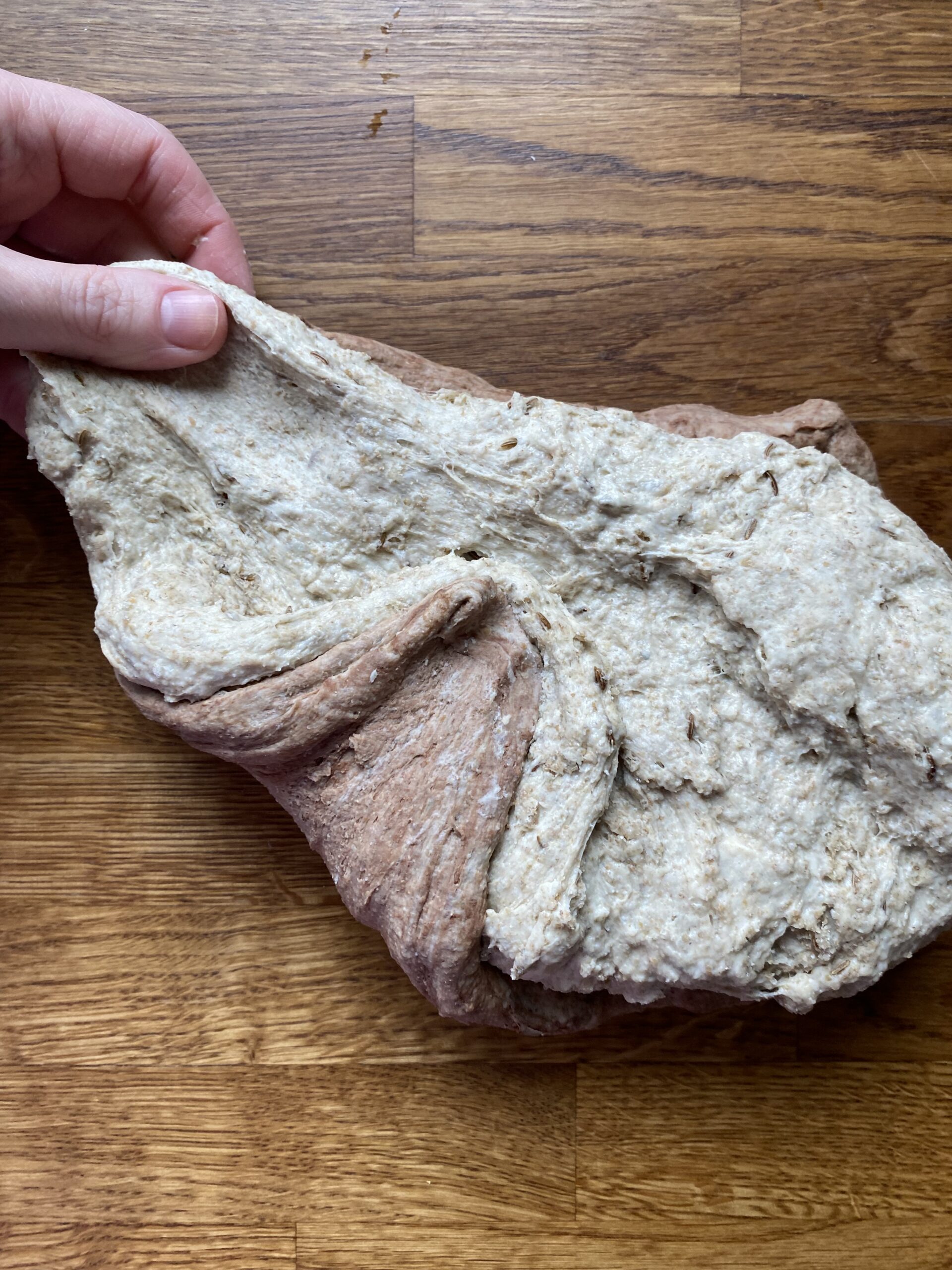The light and dark dough squished together and being shaped into a ball.