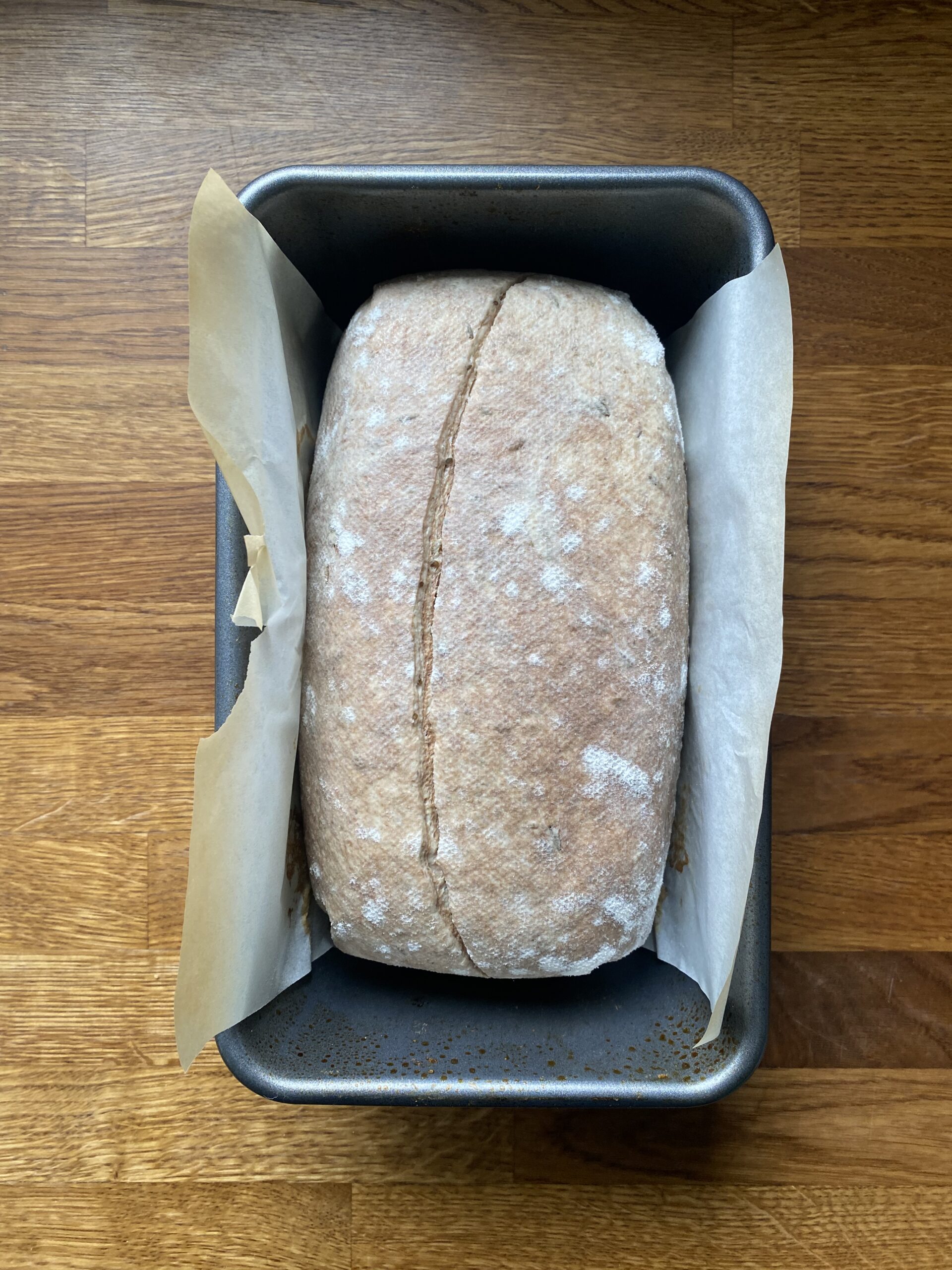 Unbaked loaf on a piece of parchment in a loaf pan, ready to bake.